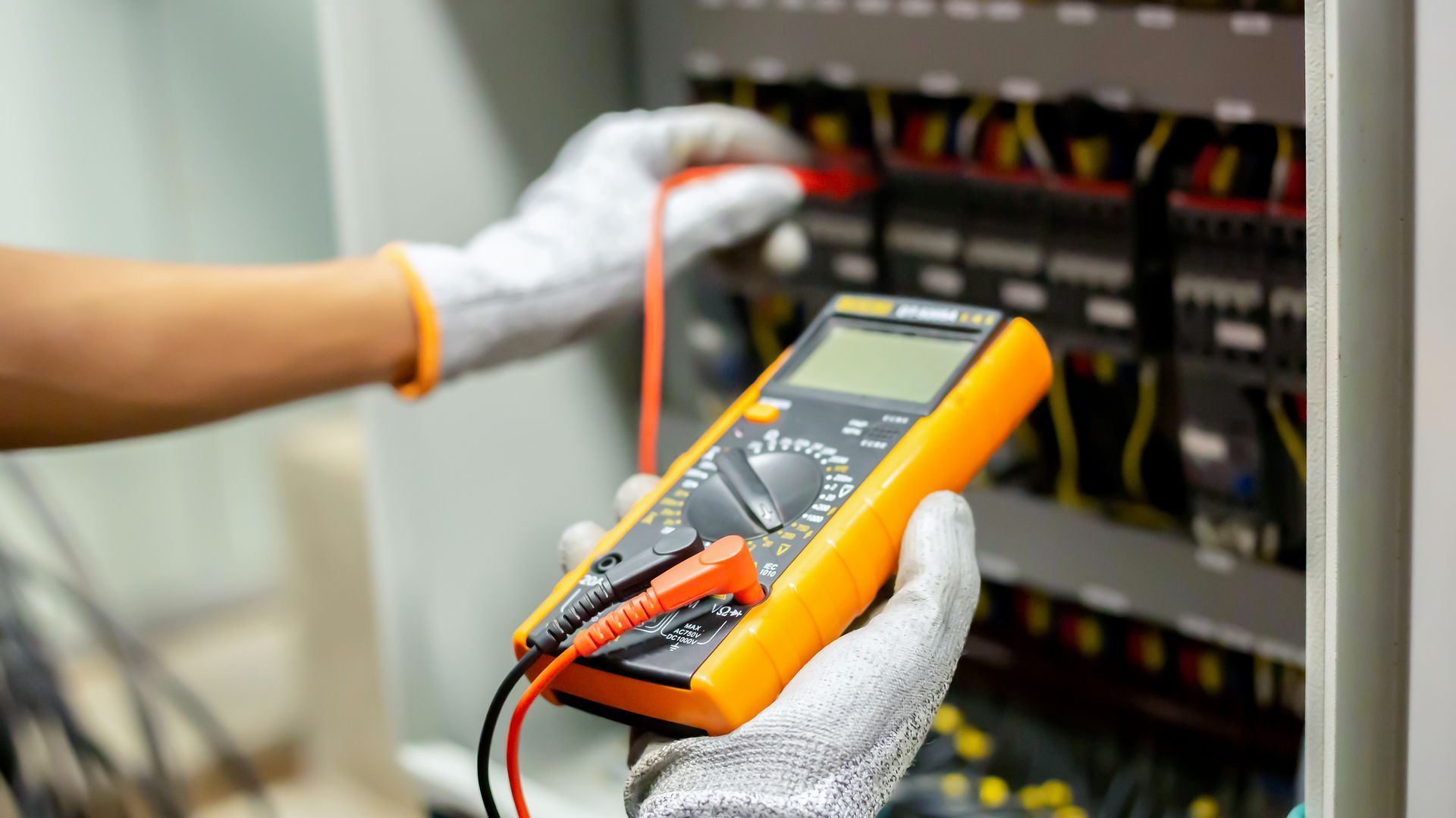 A close up of a person holding a multimeter in their hand.