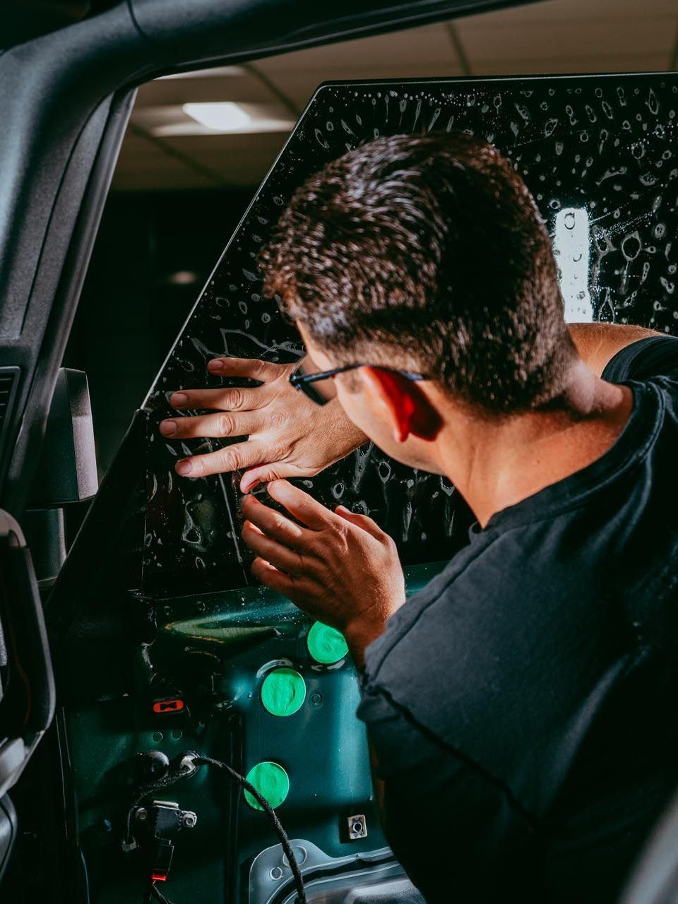 A person is cleaning a car with a pink squeegee.