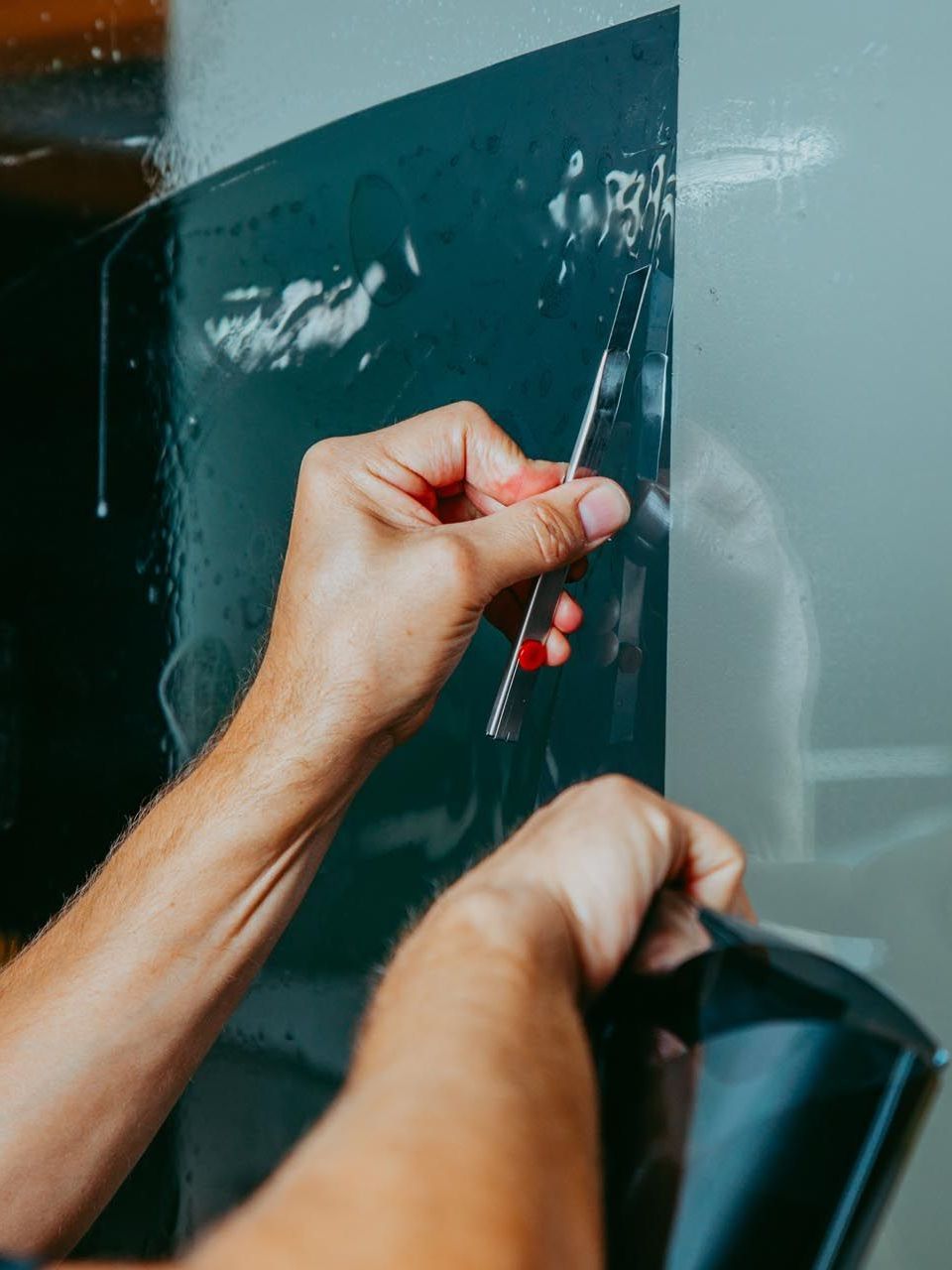 A person is cleaning a car window with a squeegee.
