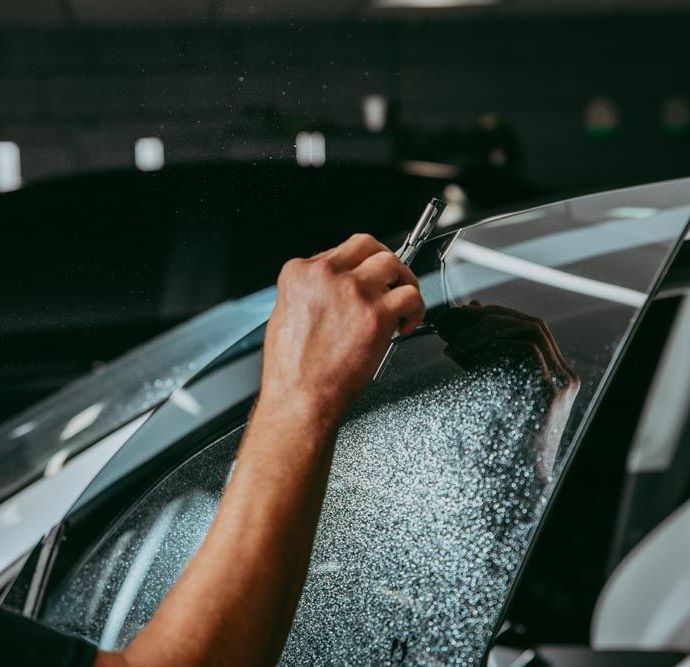 A person is applying tinted glass to a car window