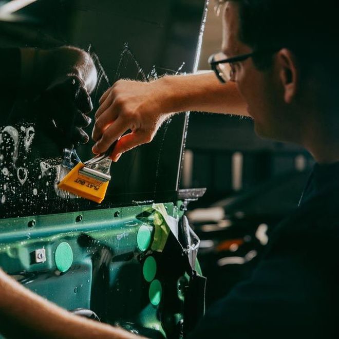 A person is applying a clear film to the hood of a car.