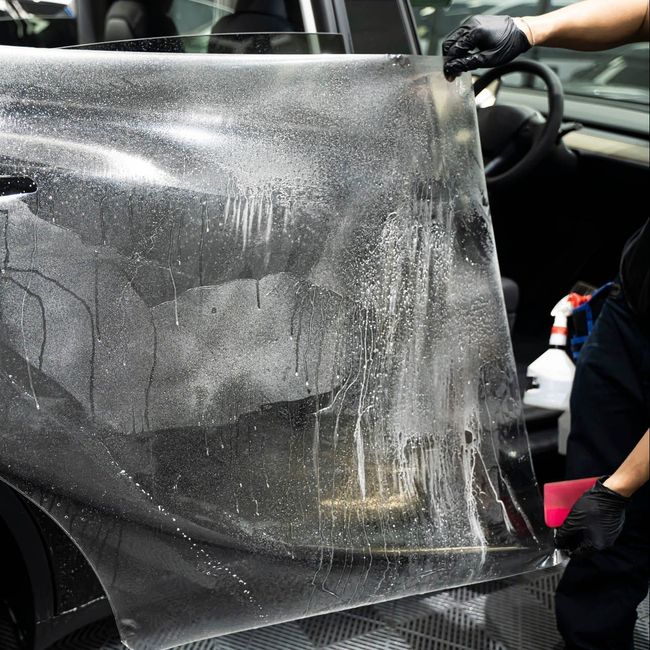 A person is washing a car wheel with foam