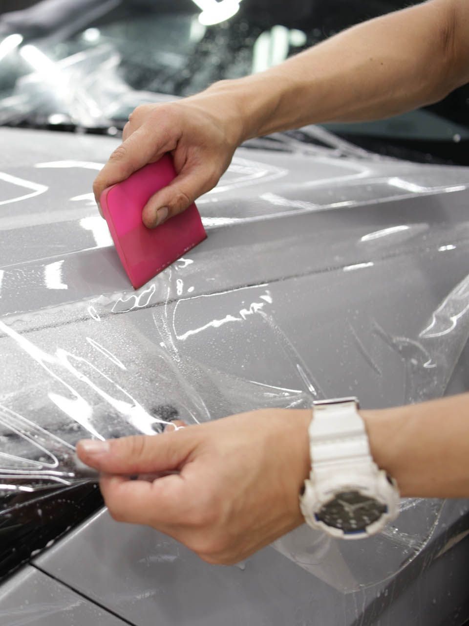 A car is covered in plastic wrap in a garage.