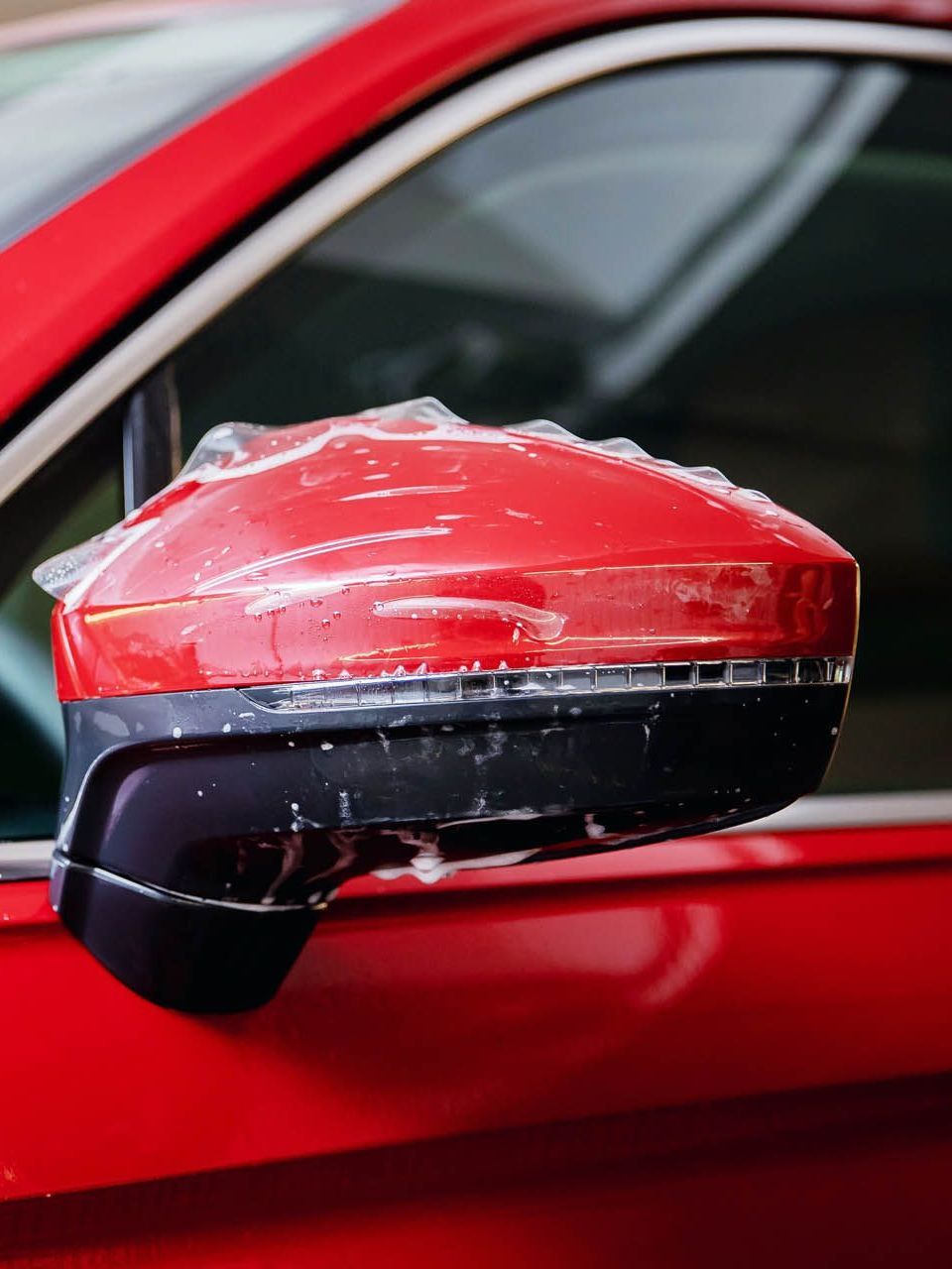 A car is covered in plastic wrap in a garage.