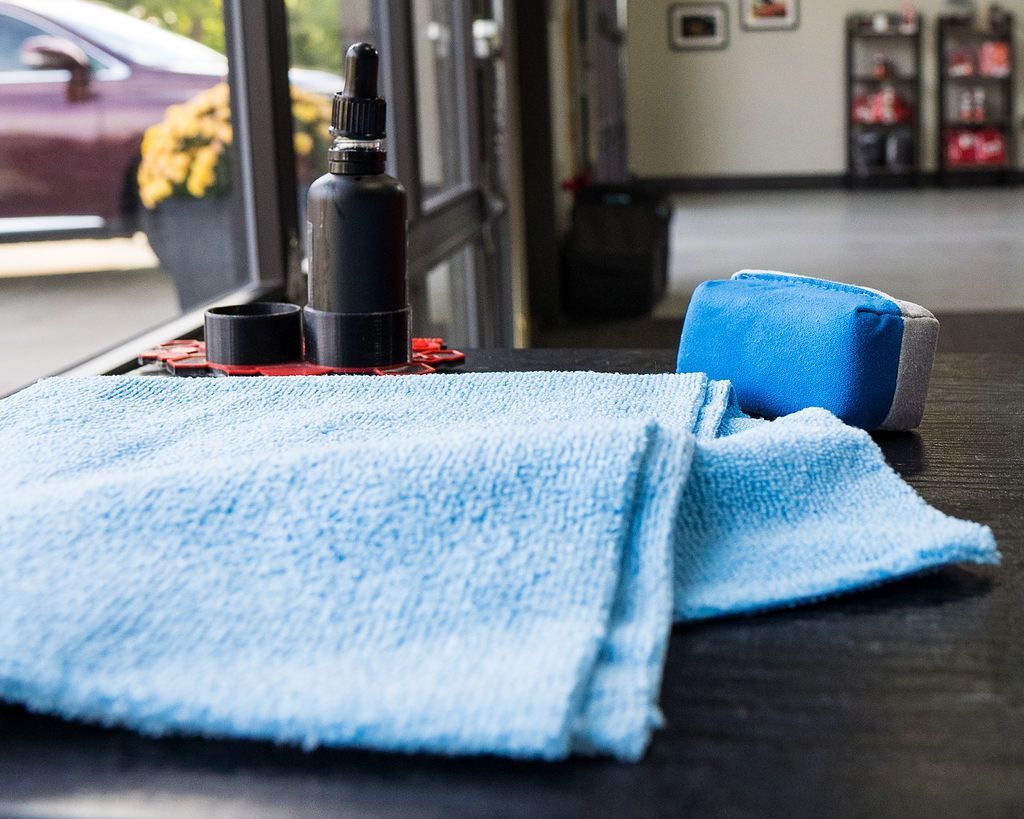 A blue towel is sitting on a table next to a bottle and a sponge.