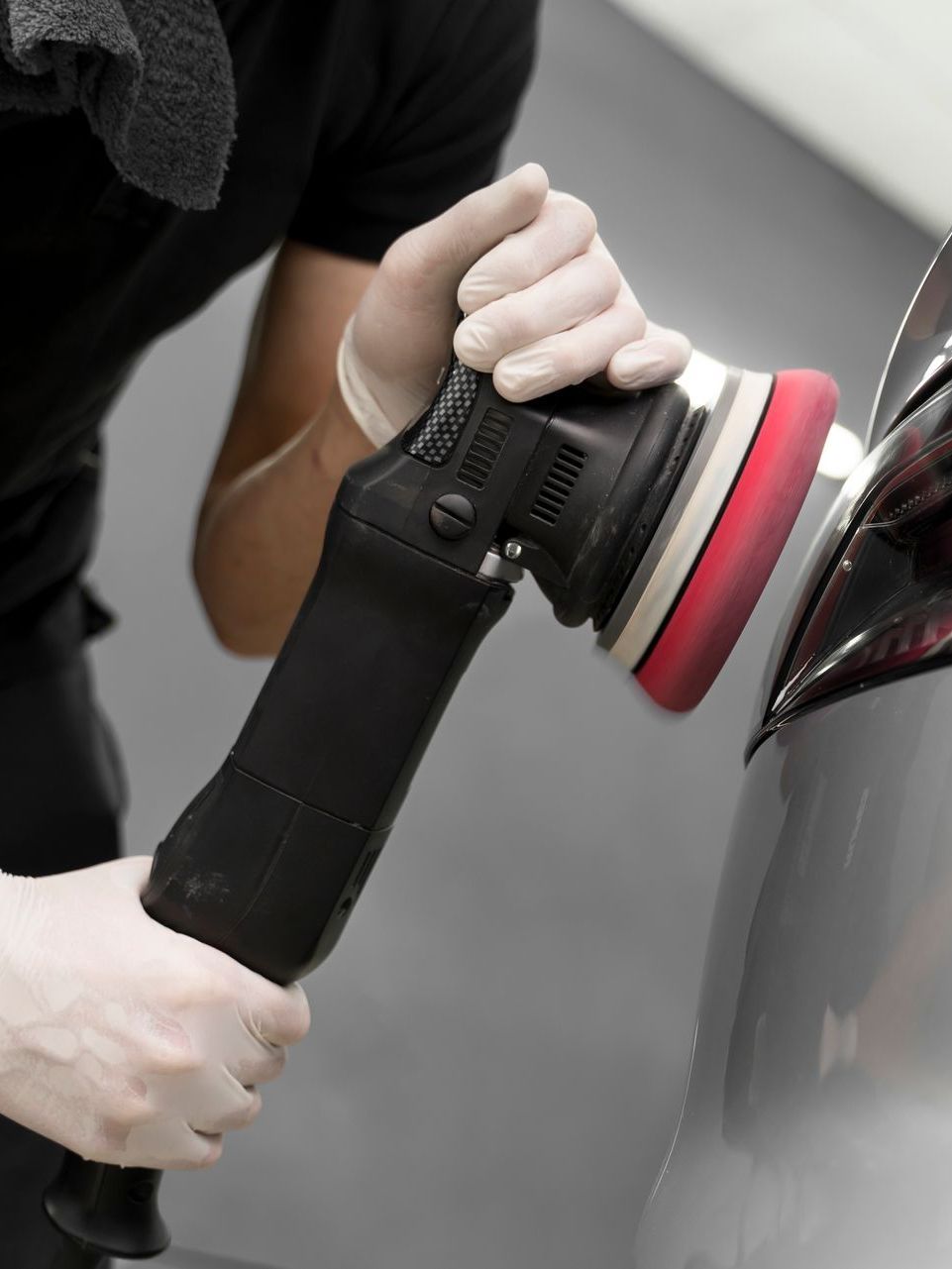 A man is polishing a car with a machine.