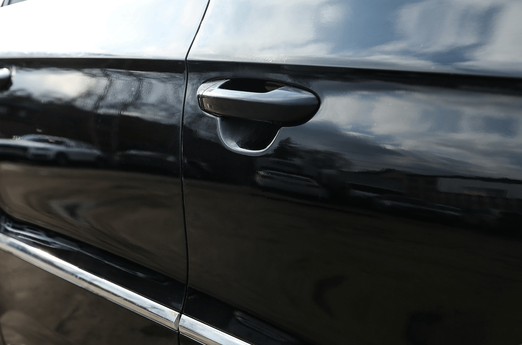A close up of the door handle of a black car.