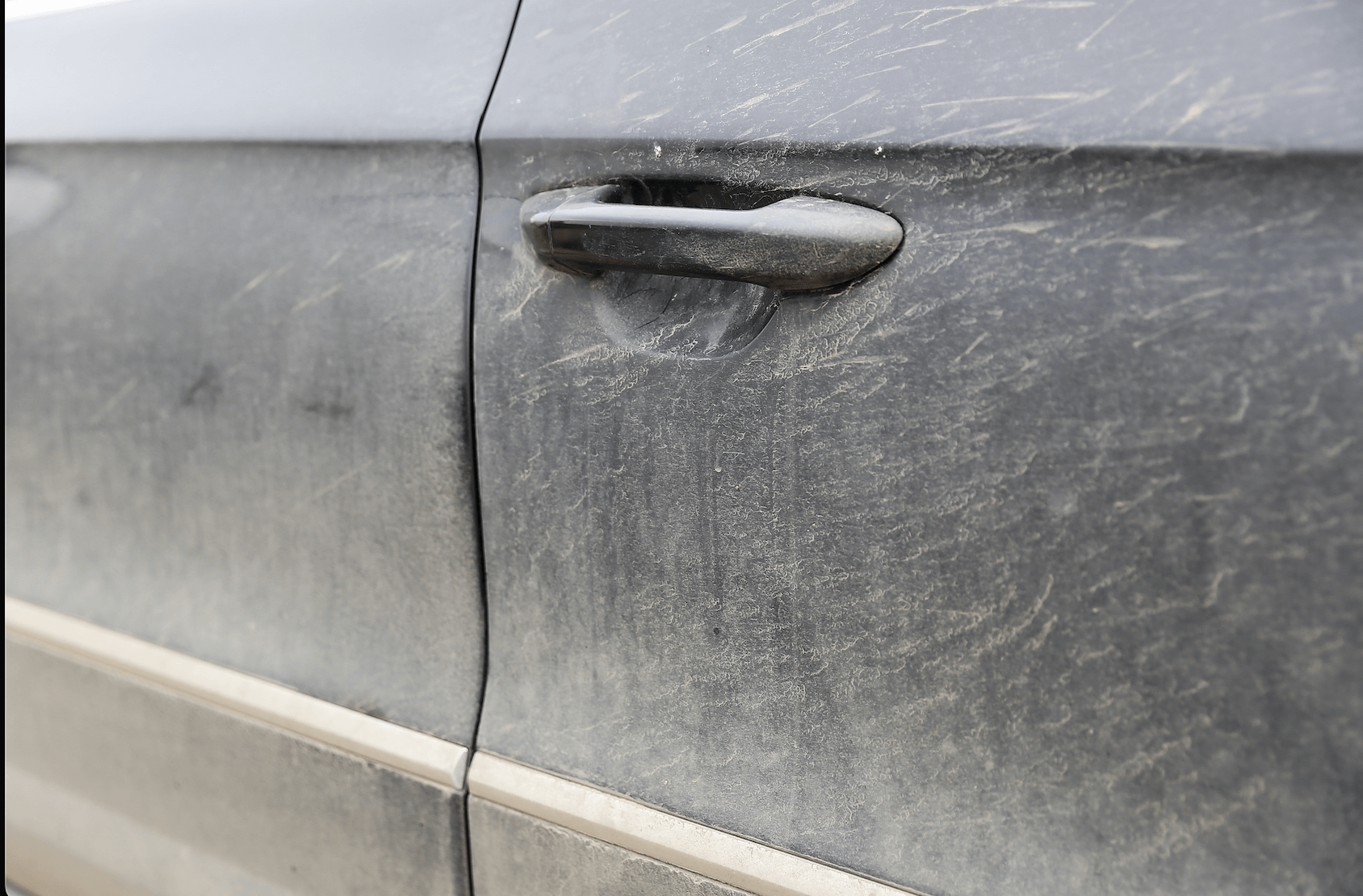 A close up of a dirty car door with a handle.