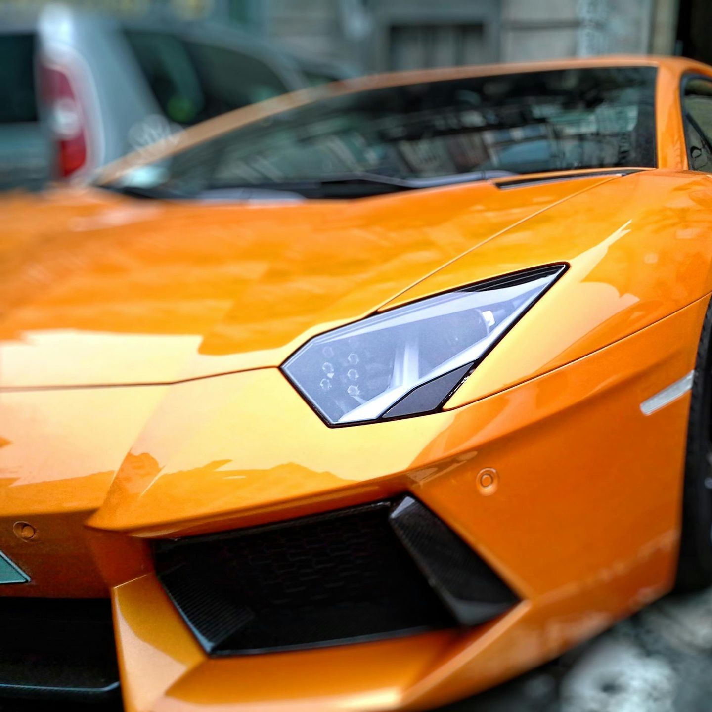 A close up of the front of an orange sports car
