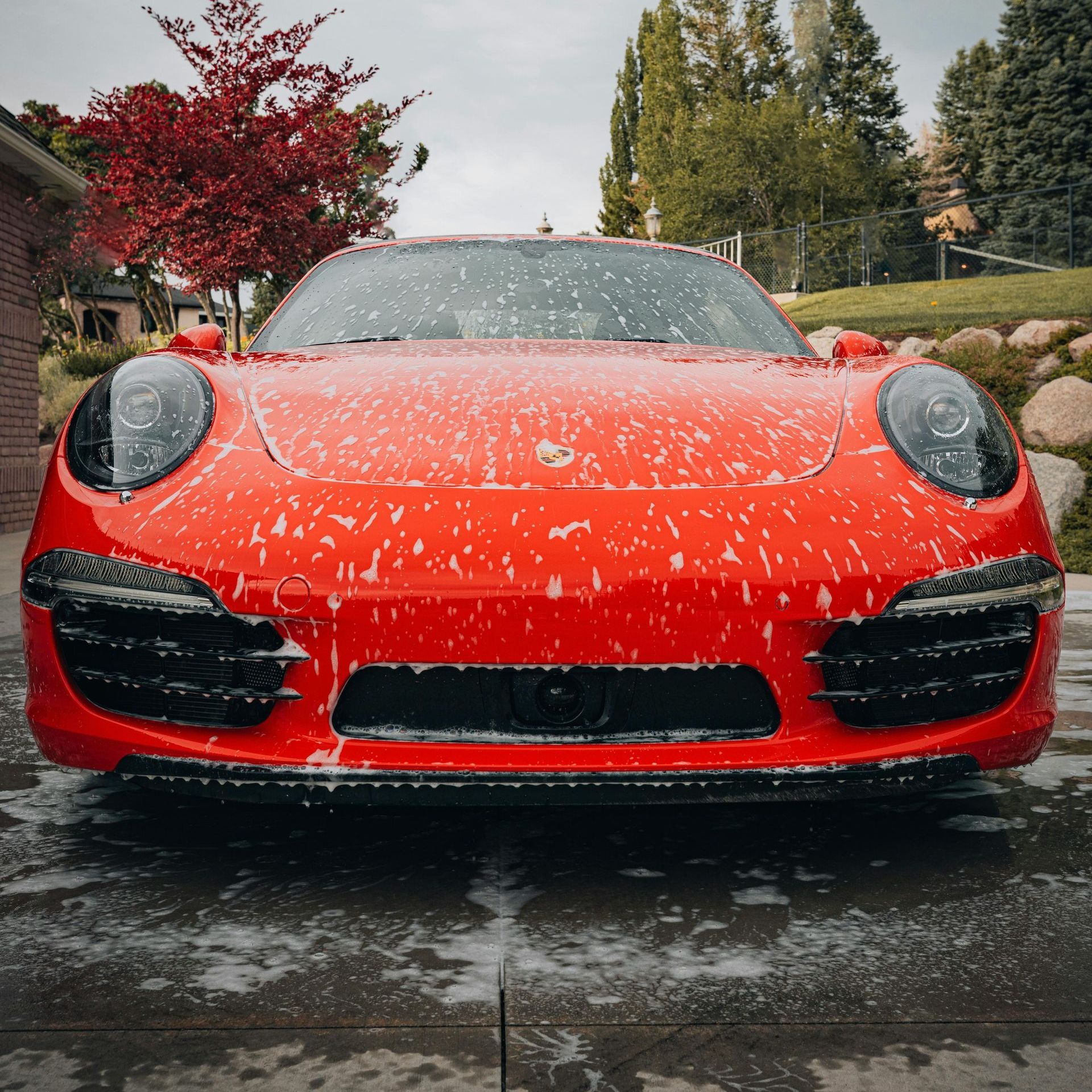 A person wearing black gloves is polishing the hood of a red car.