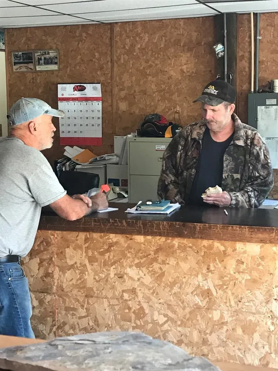 Two men are standing at a counter in a store talking to each other.