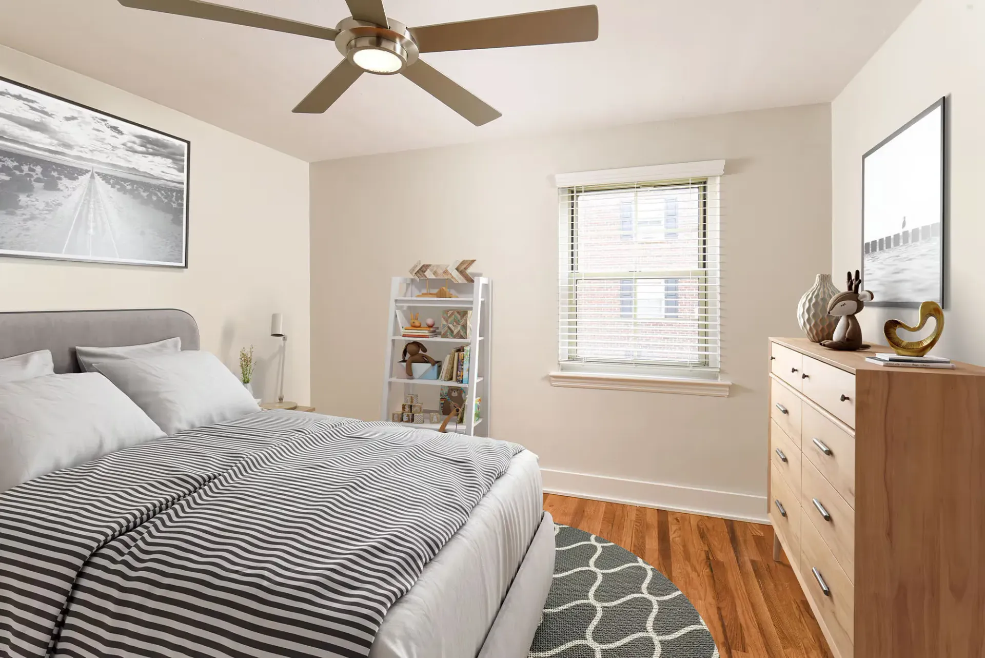 Bedroom in an apartment with a bed, dresser, window, and ceiling fan.