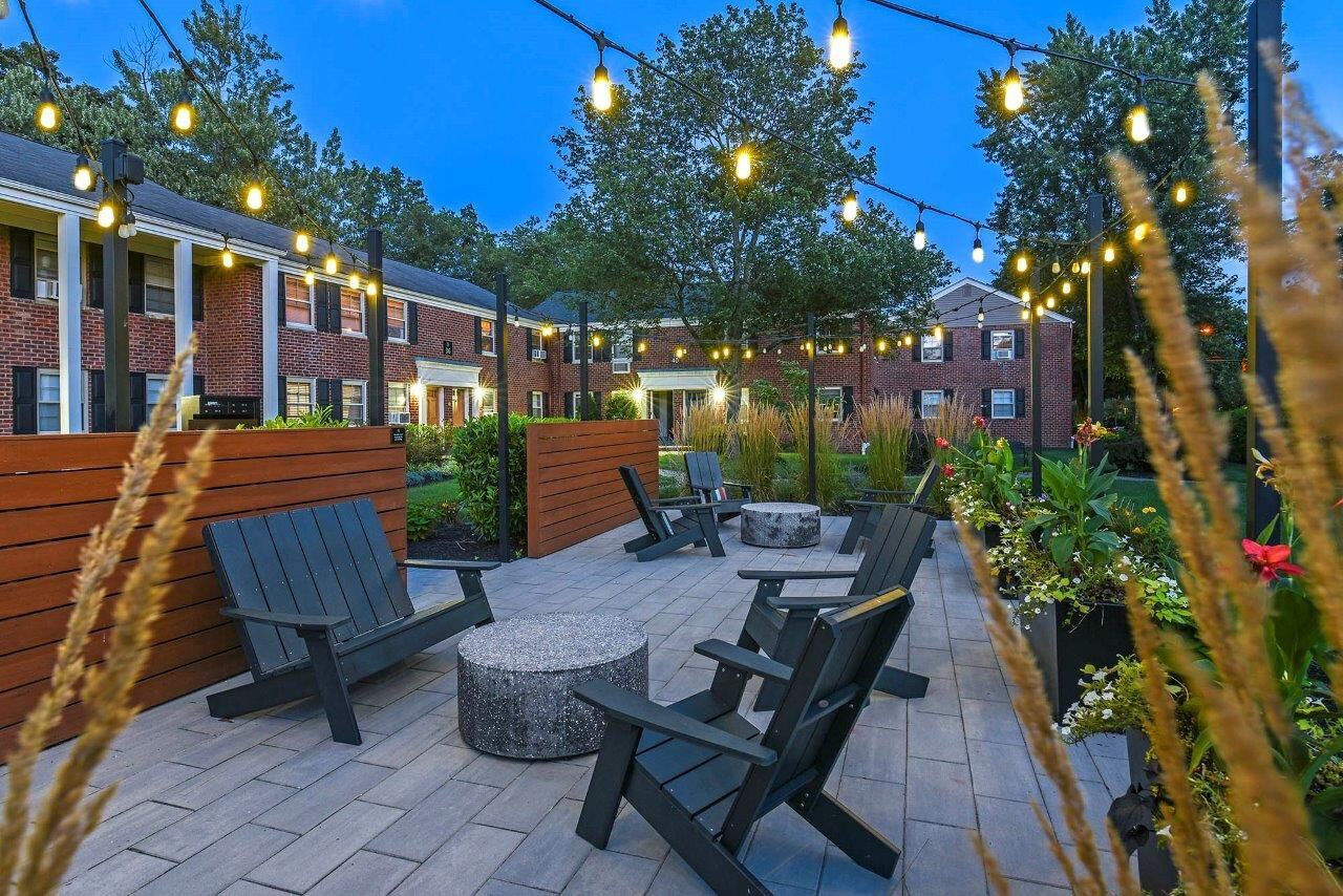 Outdoor communal courtyard with string lights, Adirondack chairs, and planters.