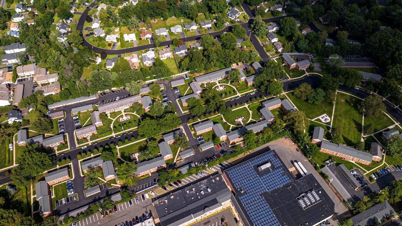 Aerial view of a multi-building apartment community with parking lots and green spaces.