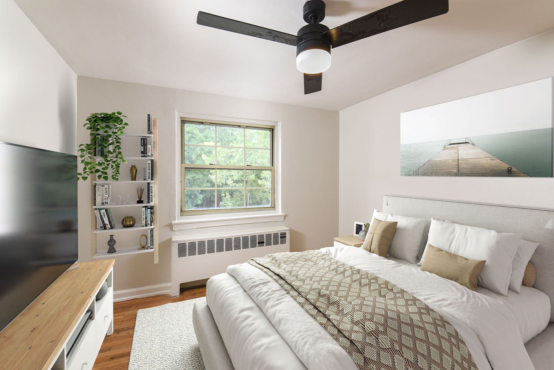 Cozy apartment bedroom with a large window, bed, ceiling fan, and a bookshelf.