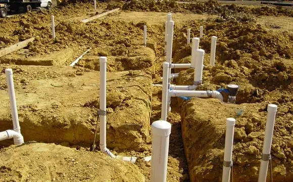 Wooden deck attached to a two-story house with green grass and a bright blue sky.