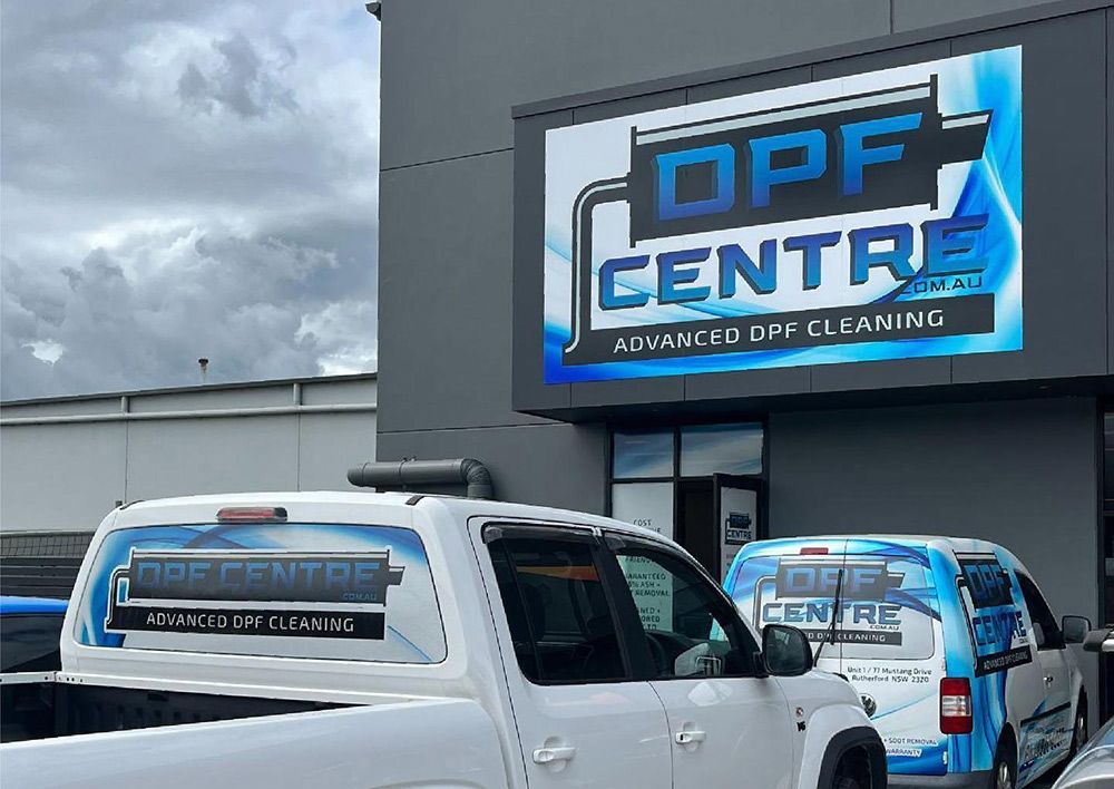 Two Trucks Are Parked In Front Of A Building That Says Opf Centre Advanced Dry Cleaning — DPF Centre In Lake Macquarie, NSW