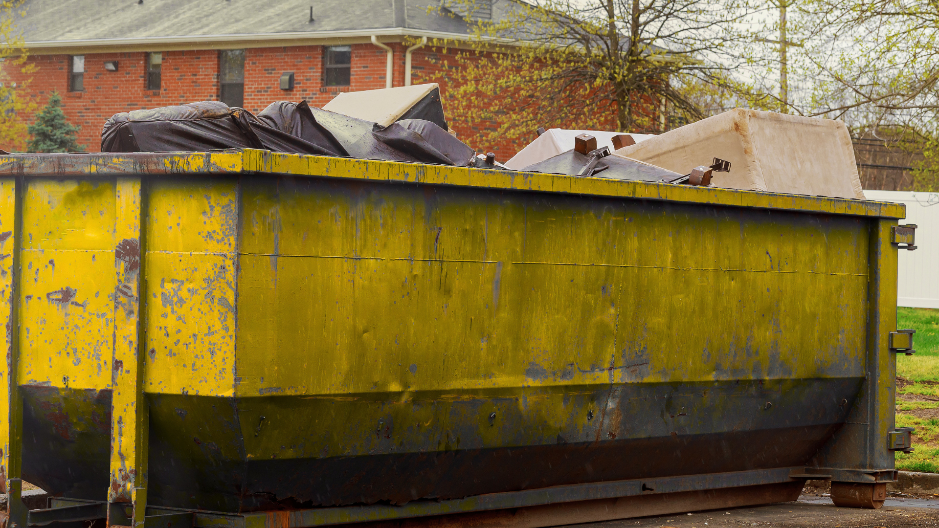 Roofing materials being disposed into large roll off dumpster