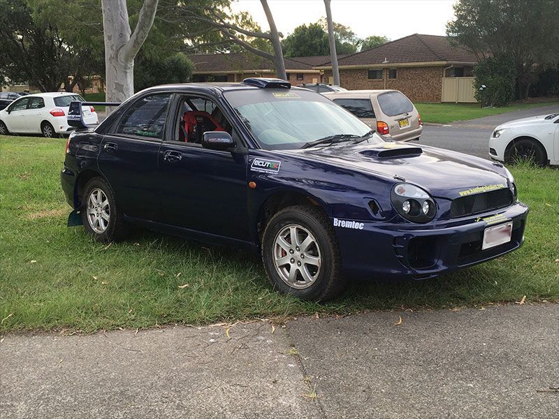 A Blue Car is Parked in the Grass on the Side of the Road — Hastings River Brake & Exhaust in Port Macquarie, NSW