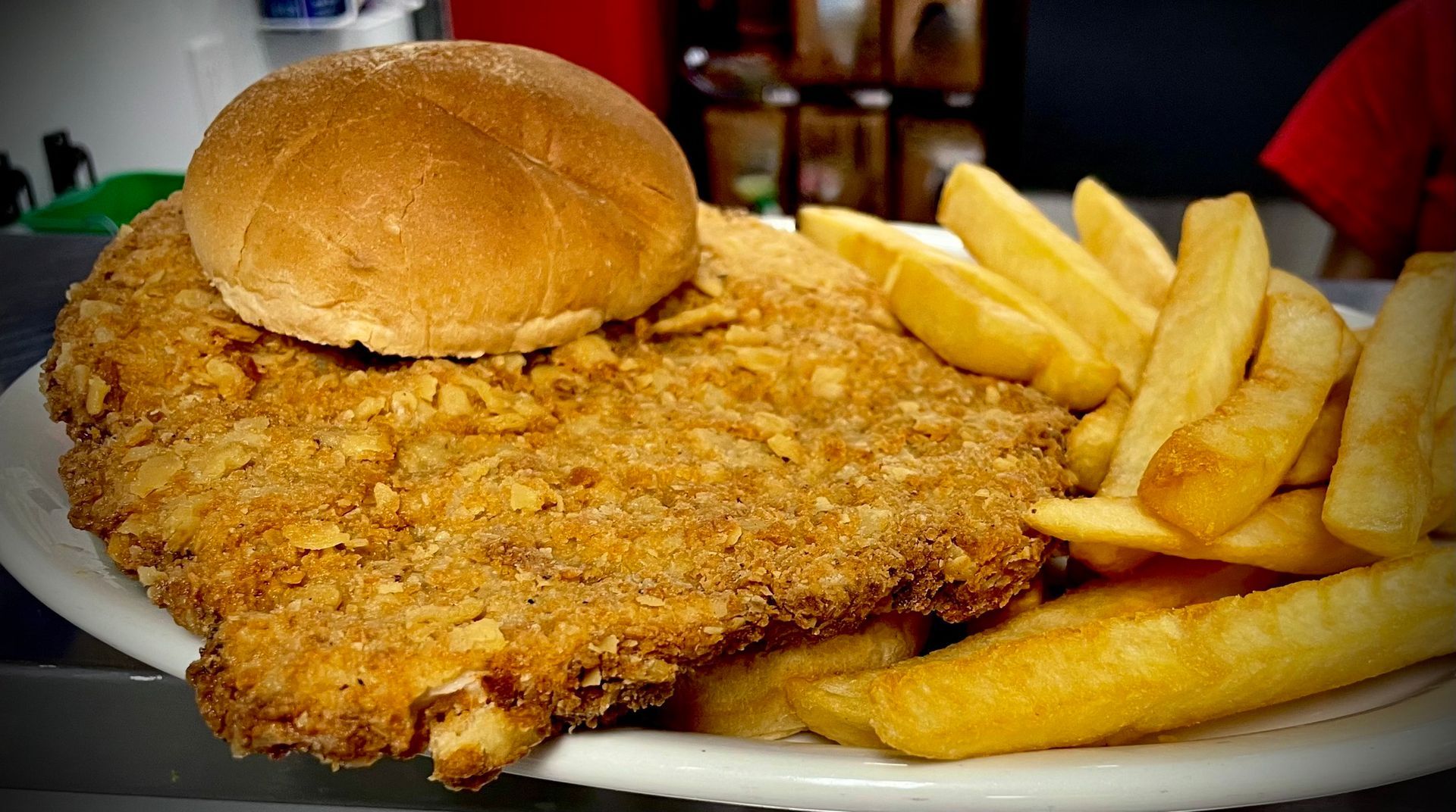 A plate of fried pork tenderloin sandwich and french fries.
