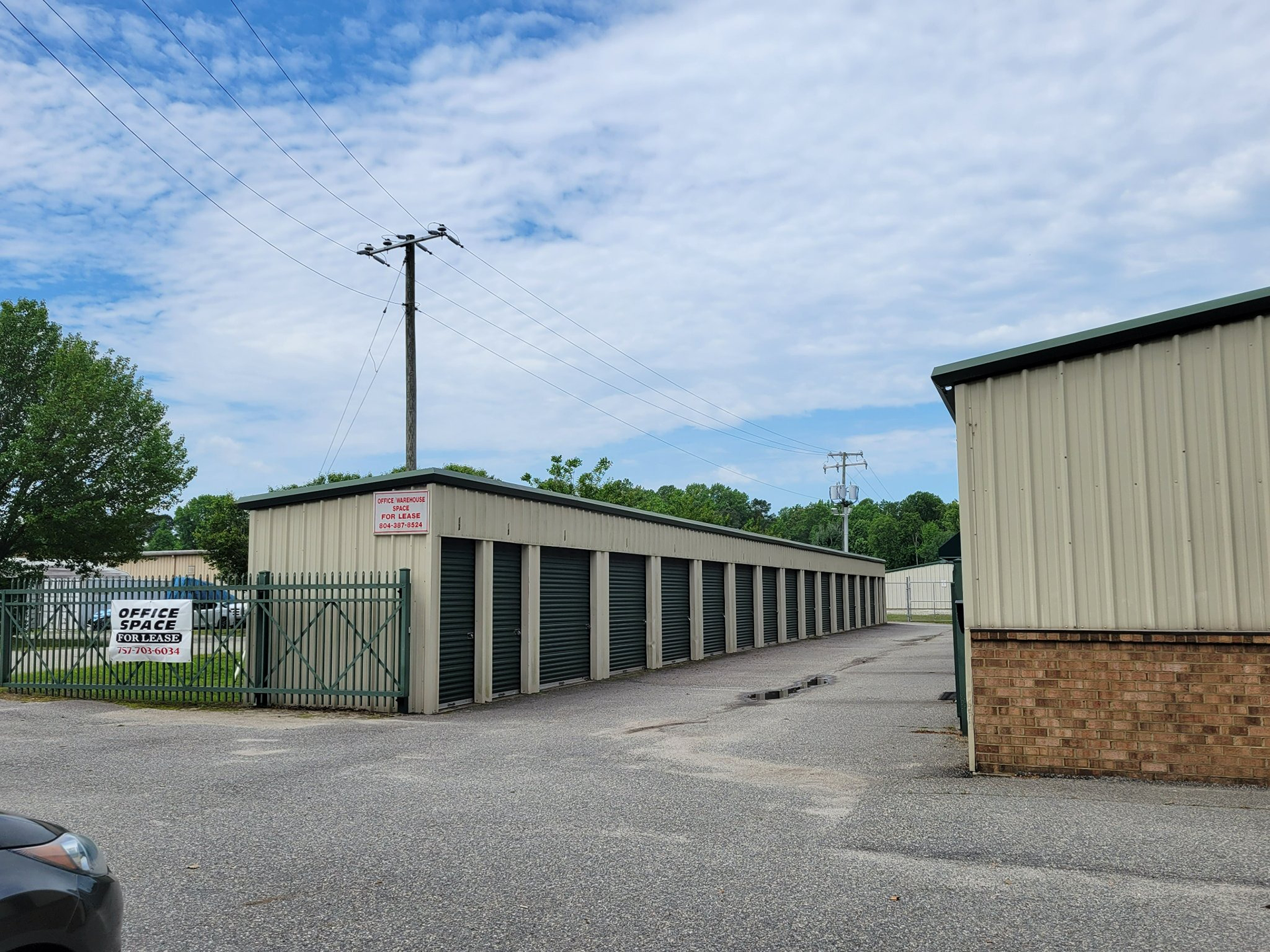 A car is parked in front of a row of storage units.