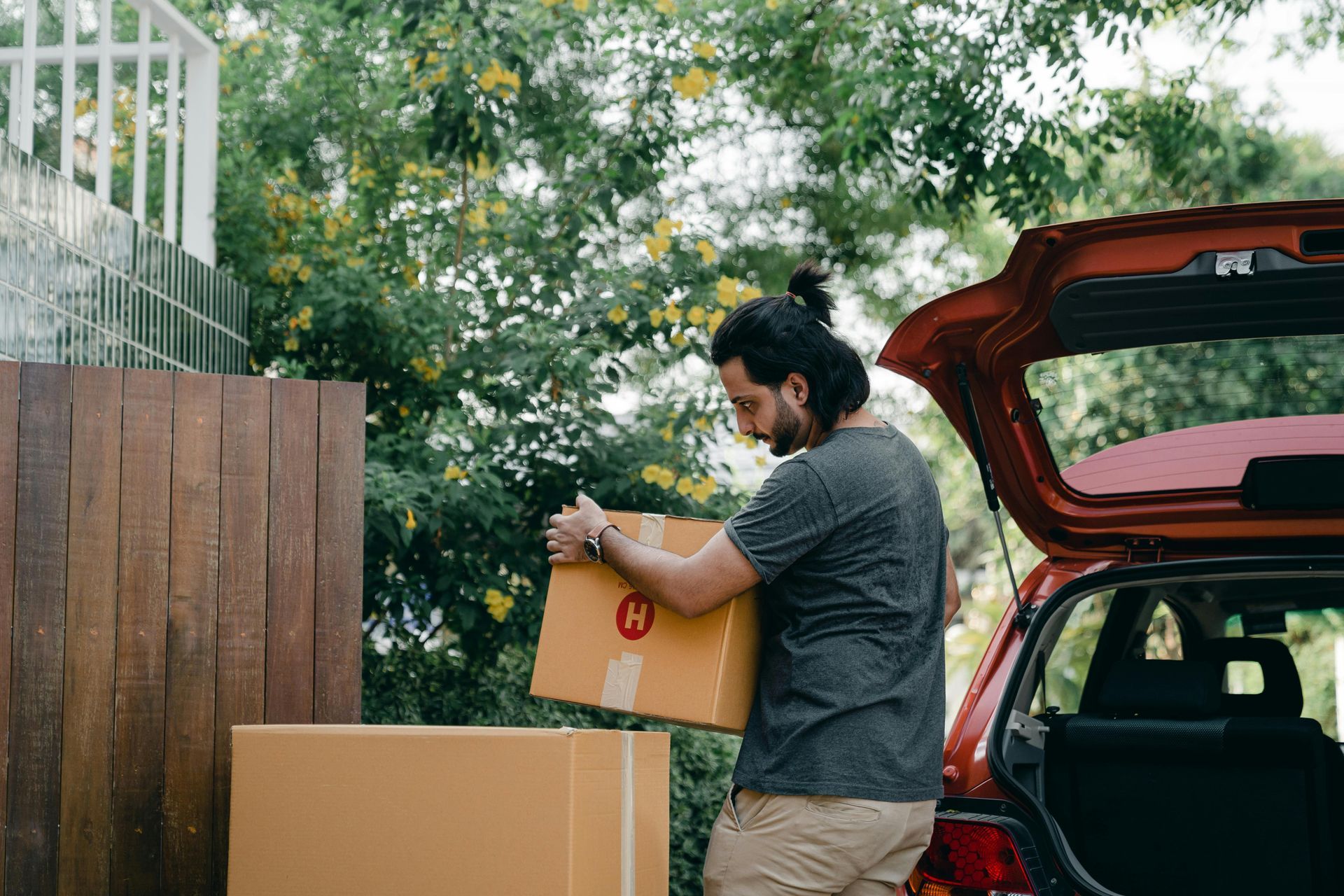 A man is loading boxes into the back of a car.