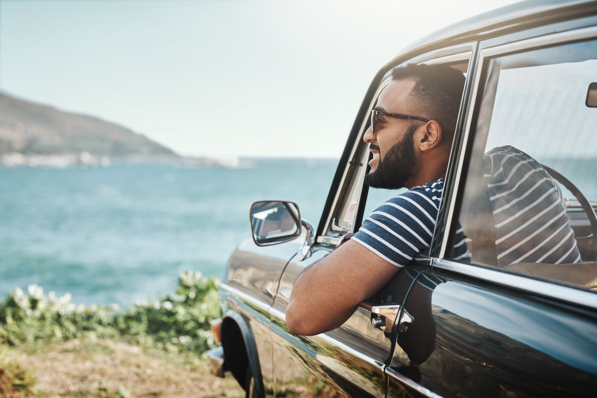 Man in car enjoying the beach on vacation.