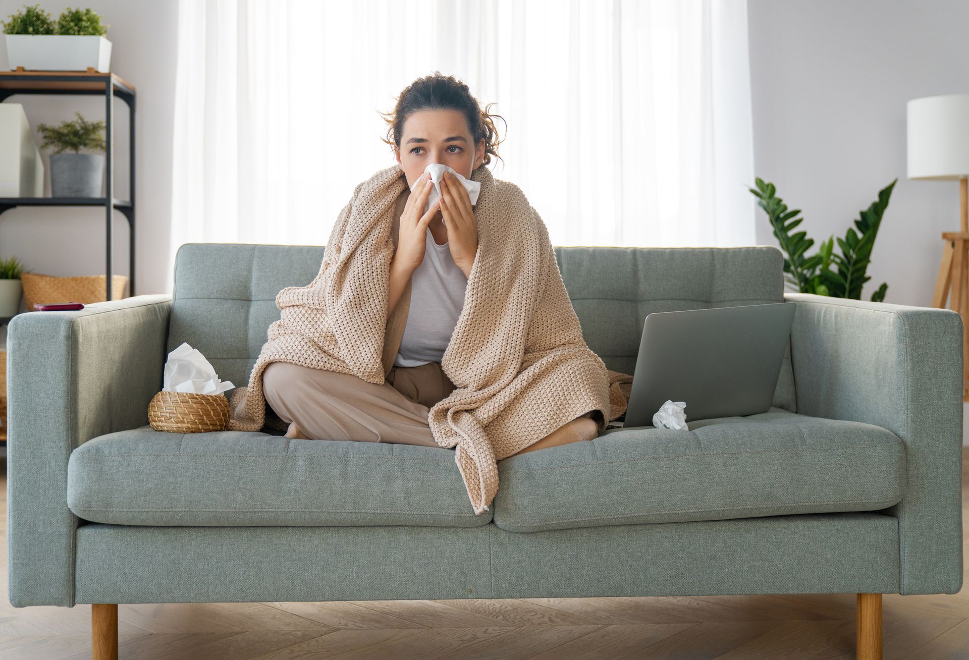 Woman on a couch with a tissue representing the need for  indoor air quality for allergy relief.