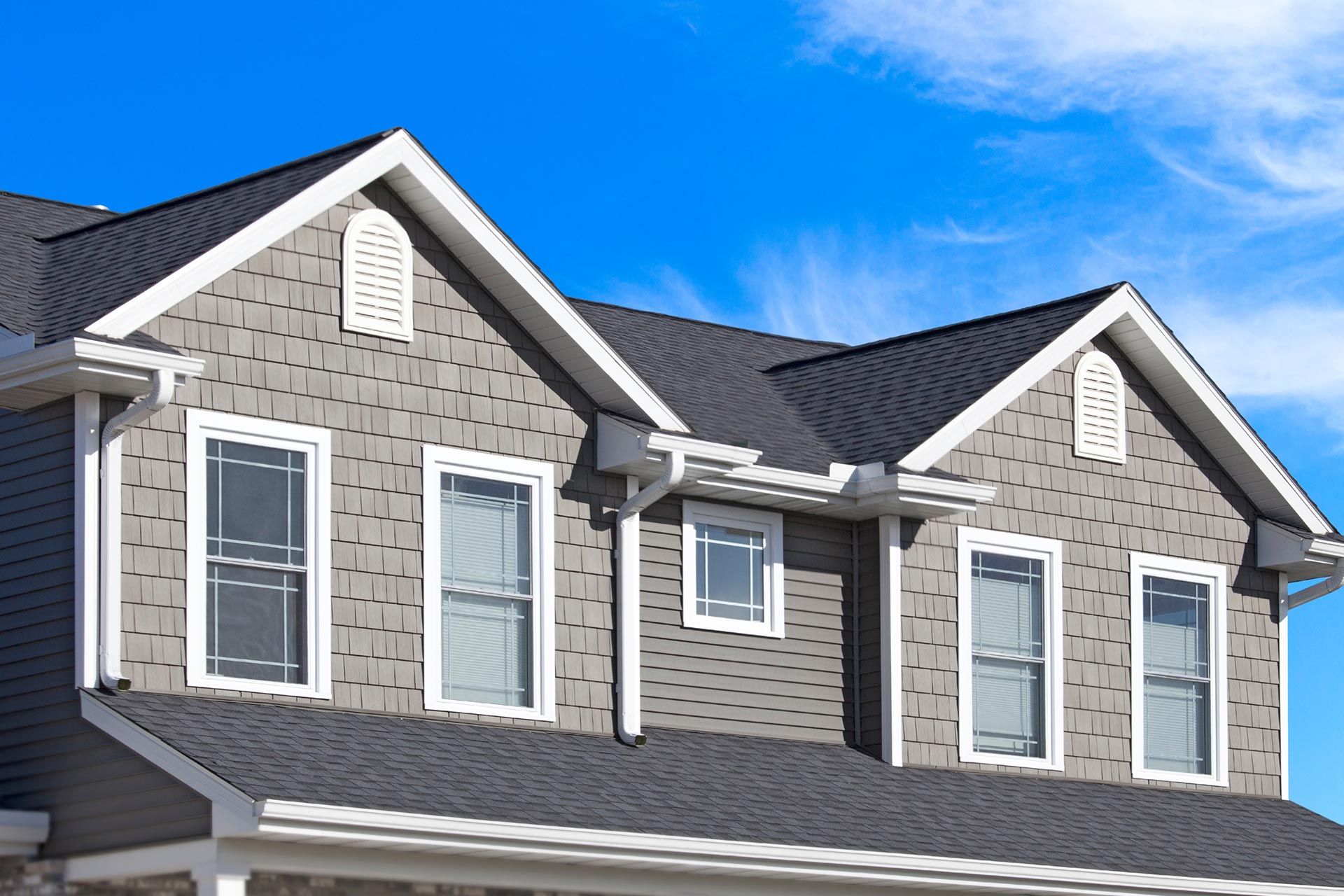 Gray house roof and dormer windows against a bright blue sky Gray house roof and dormer windows against a bright blue sky