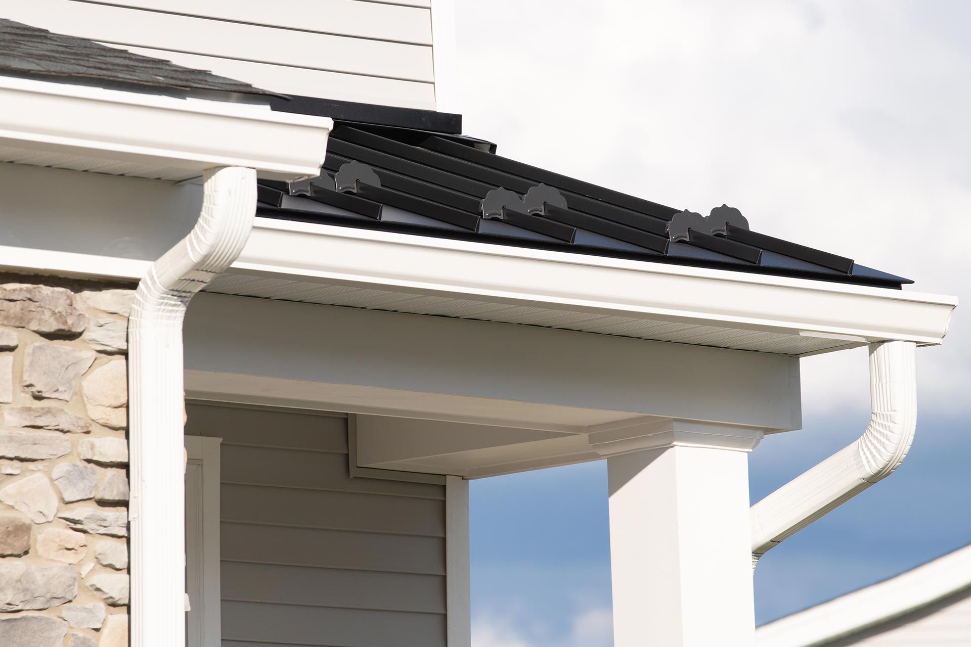 House roof and white gutters with dark shingles against a cloudy sky House roof and white gutters with dark shingles against a cloudy sky
