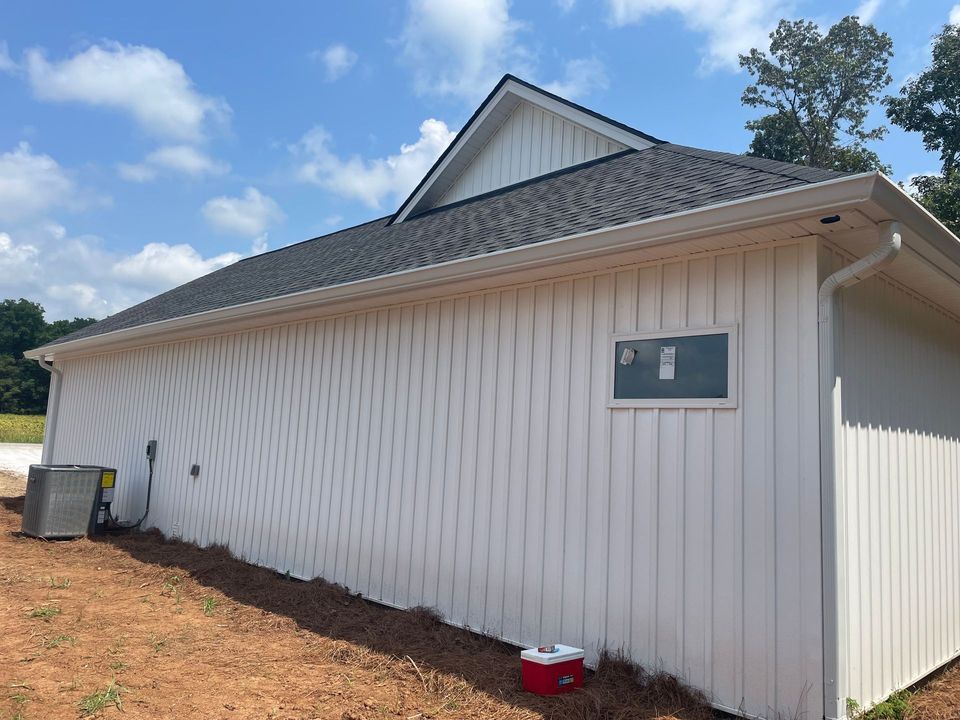 White-sided building with a dark roof and small window on a dirt lot under a blue sky White-sided building with a dark roof and small window on a dirt lot under a blue sky