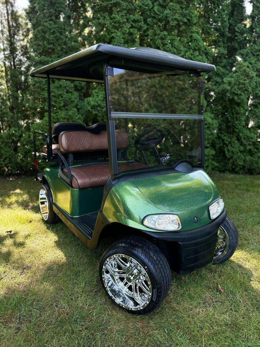 A green golf cart is parked in the grass.
