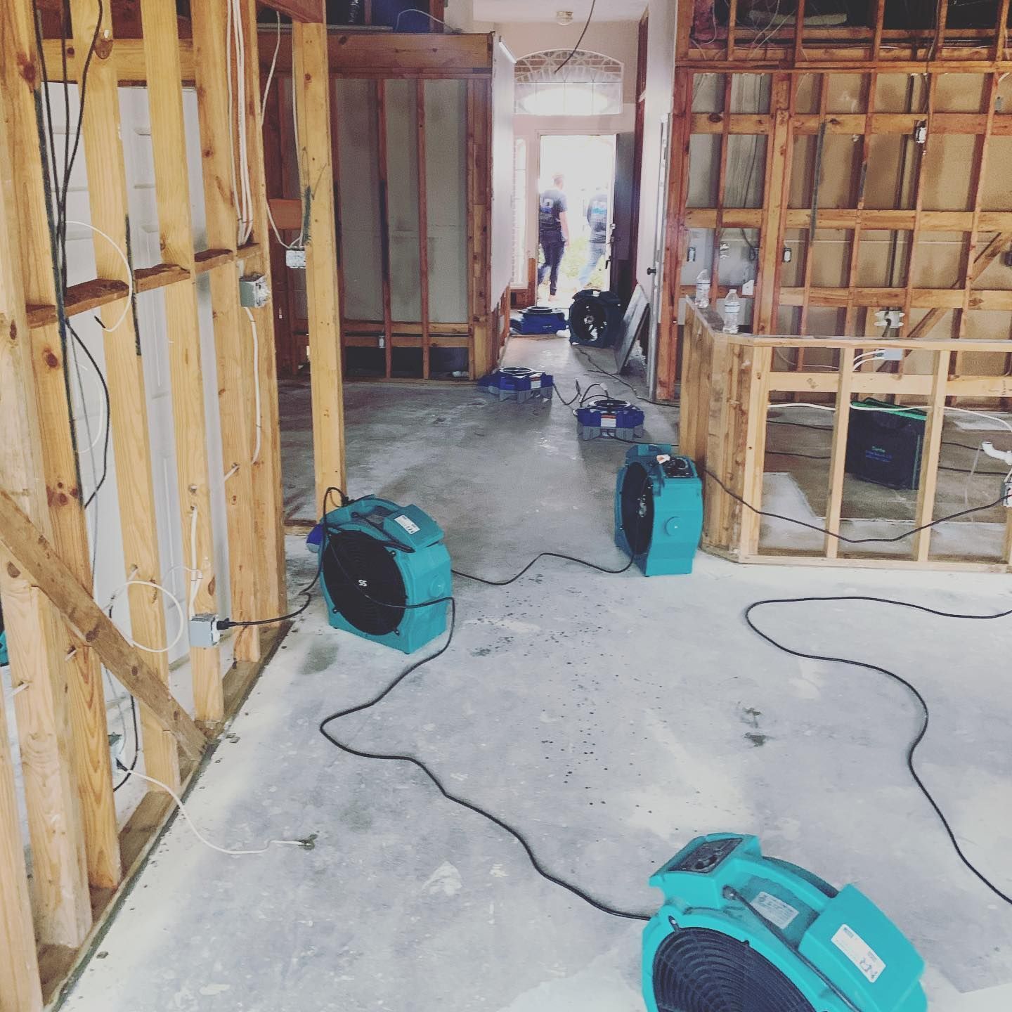 Interior with fans drying a flooded area between wooden walls.