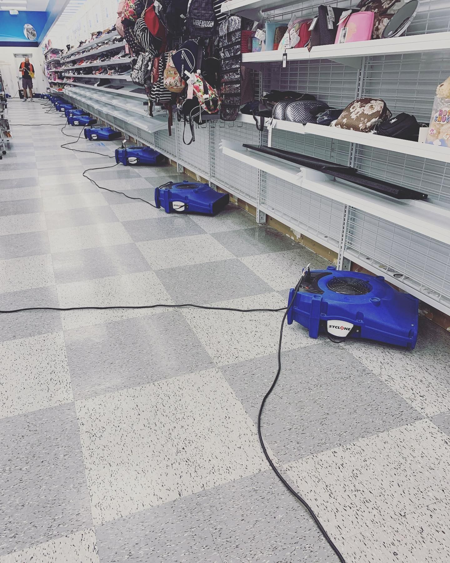 Blue floor buffers plugged in, cleaning a store aisle.