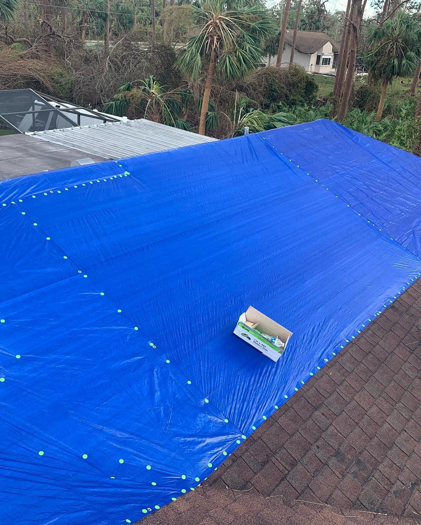 Blue tarp covering a roof; a box sits on the tarp.