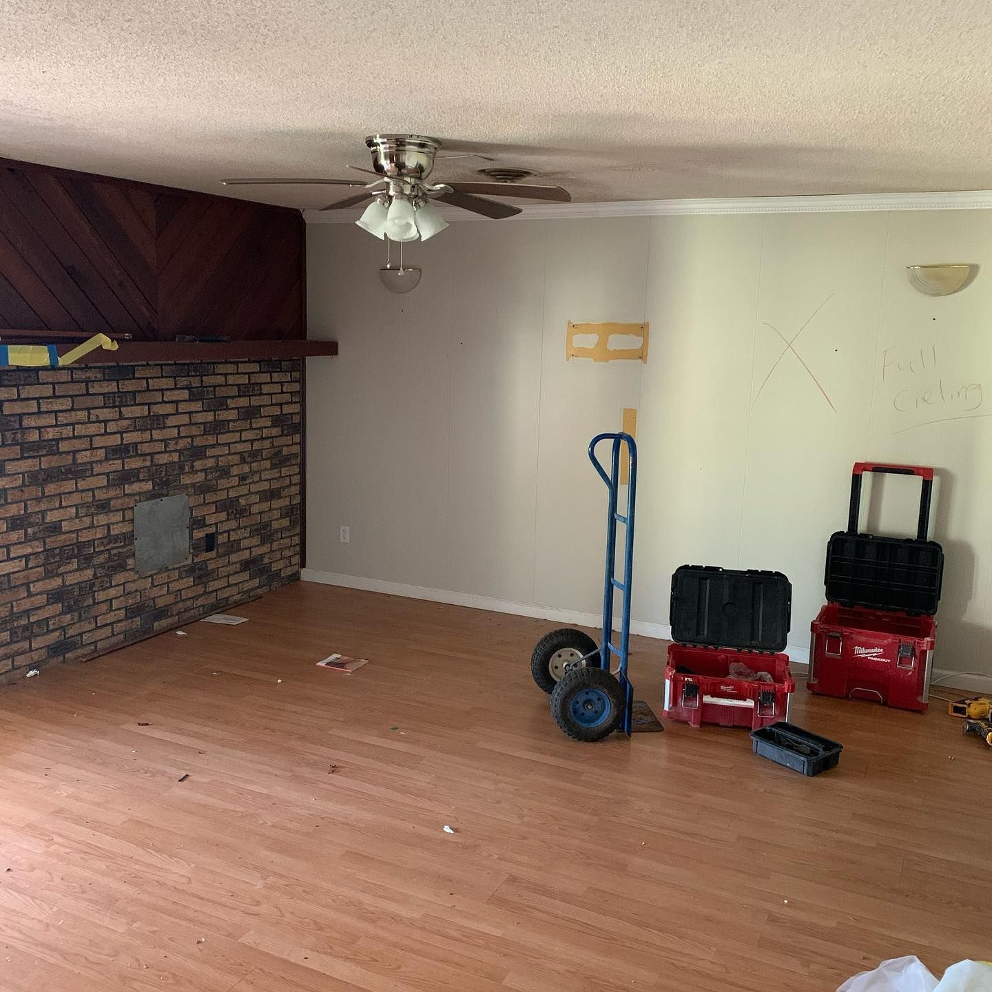 A living room with a brick fireplace, wooden floor, and tools.