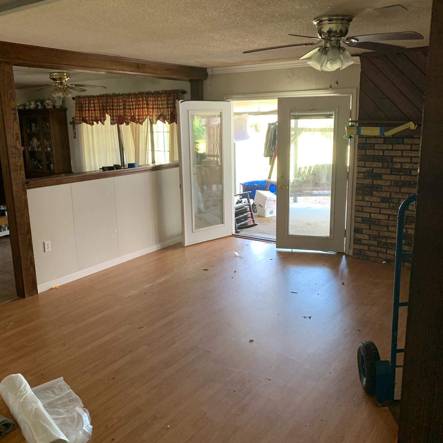 Spacious living room with wood flooring, French doors, and brick accent wall.