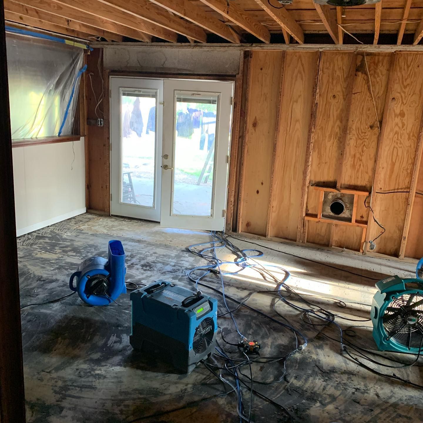 Room being remediated for water damage, with fans and exposed wall studs visible.