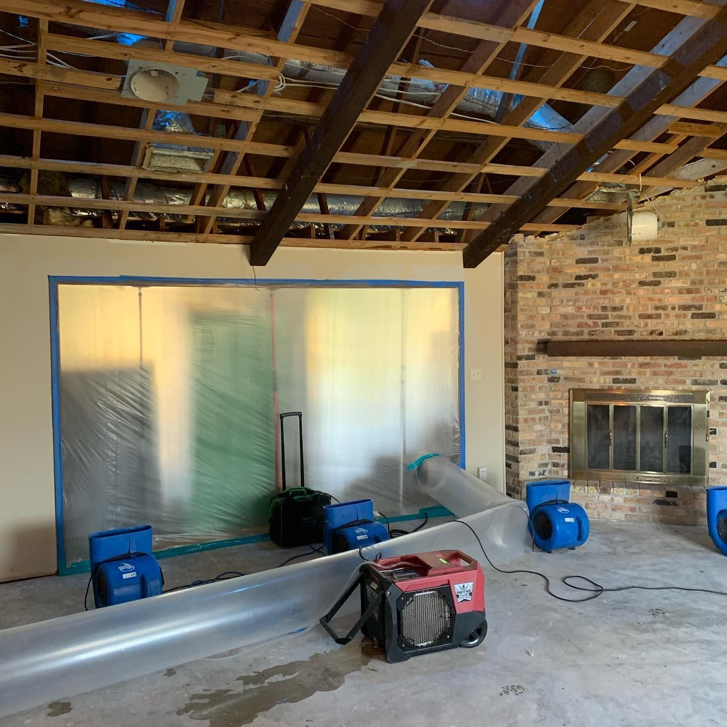 Room undergoing restoration; fans, dehumidifiers, and a generator inside.