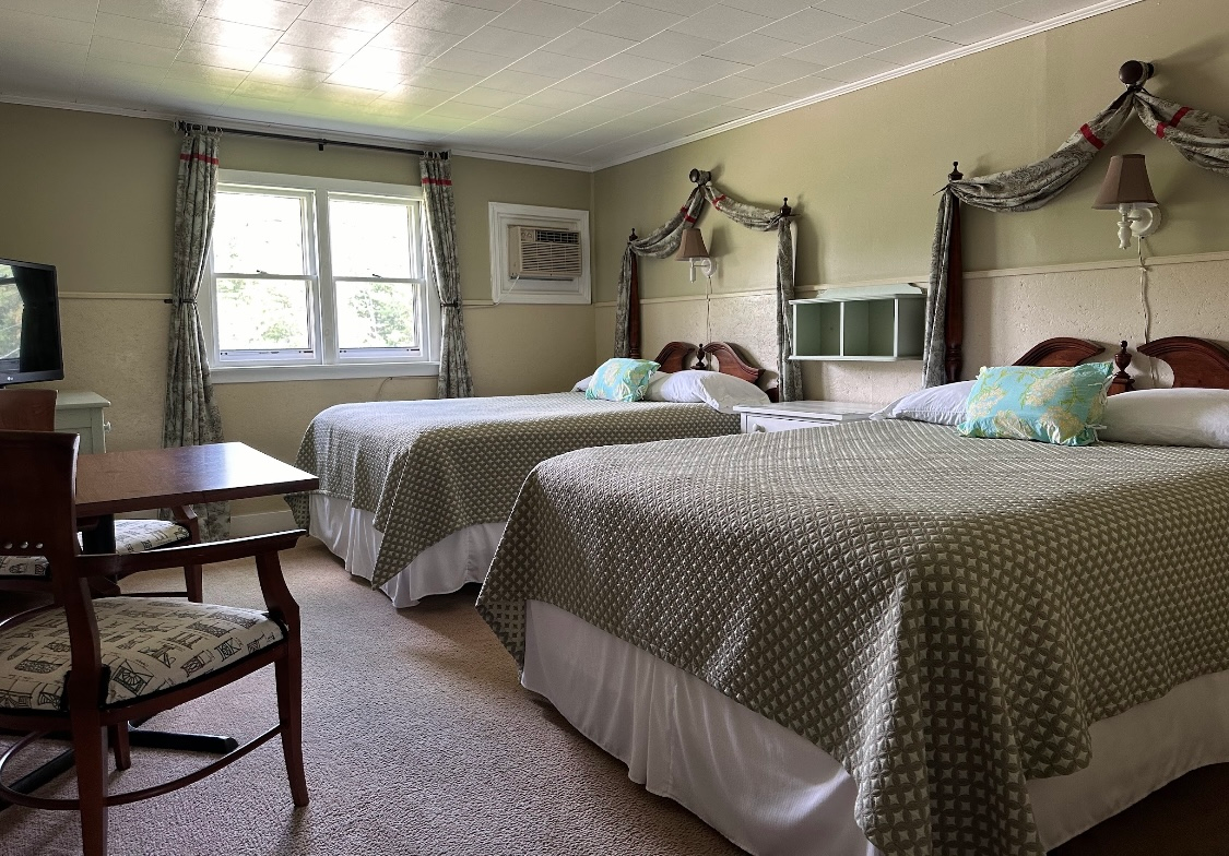 A hotel room with two beds , a table and a chair.