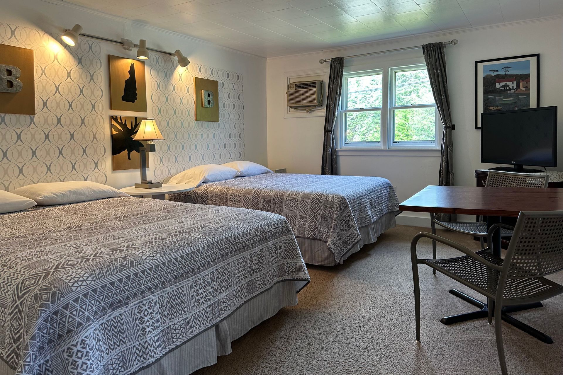 A hotel room with two beds , a table and a television.
