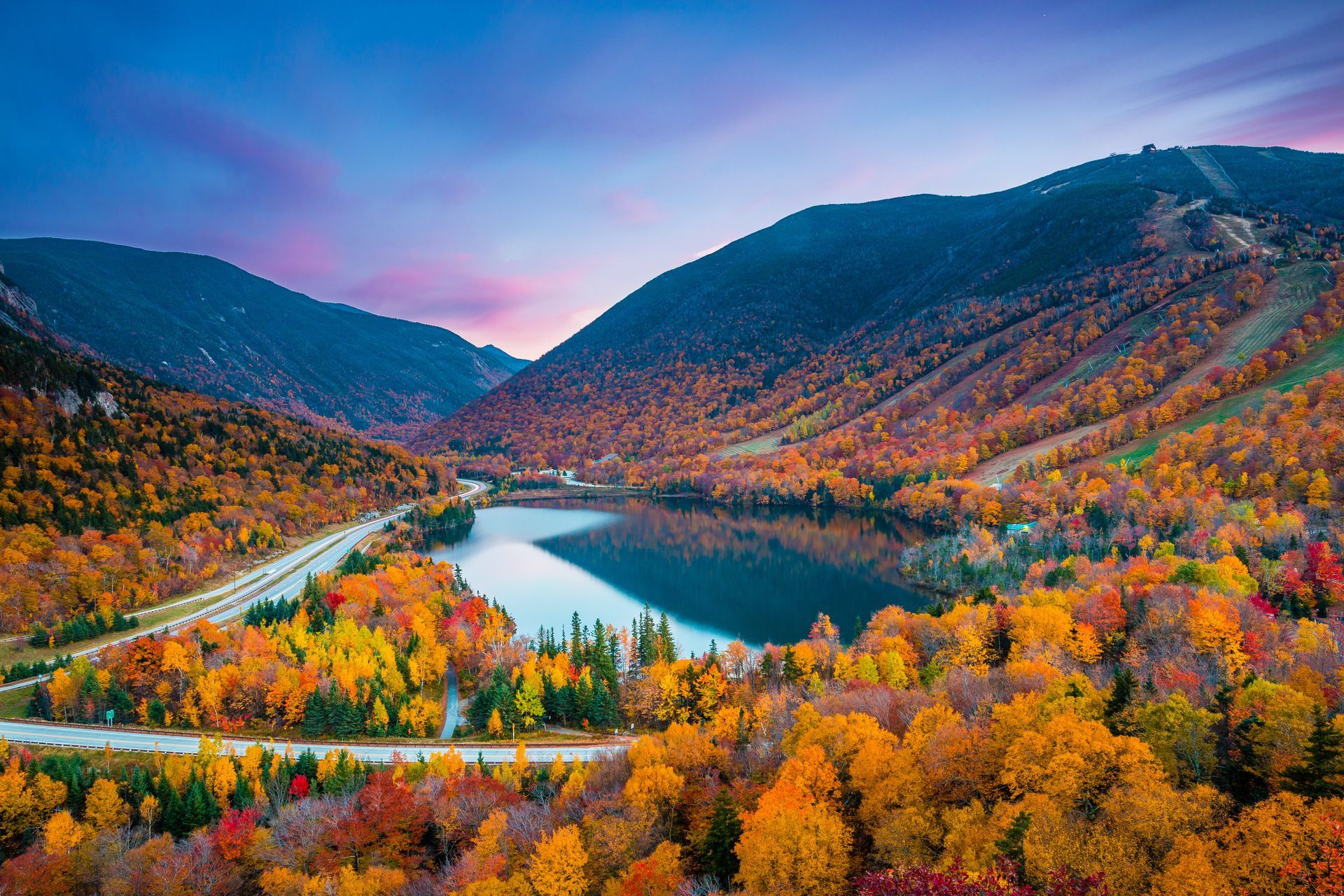 An aerial view of a lake surrounded by trees and mountains.