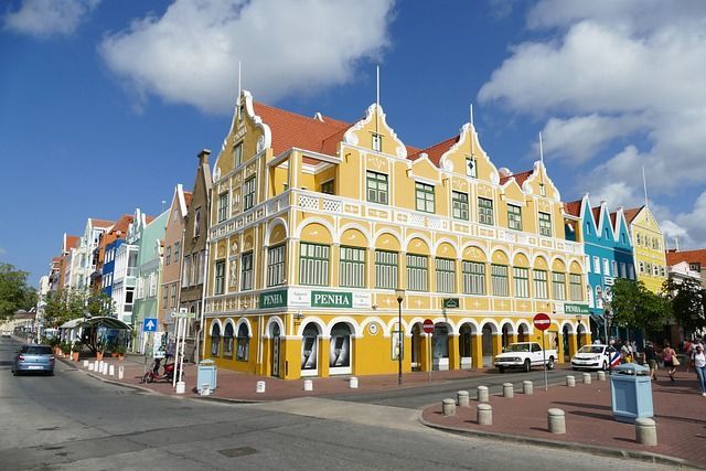 A yellow building with a red roof is on the corner of a street.