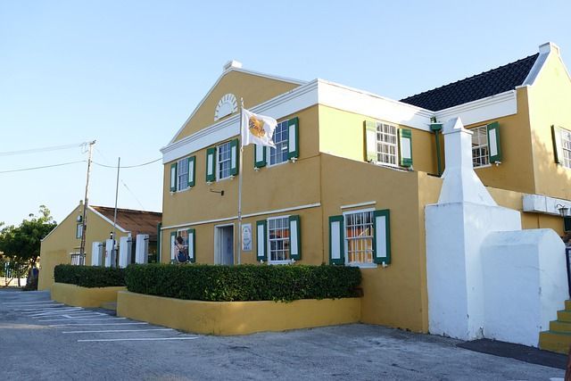 A yellow building with green shutters and a flag in front of it