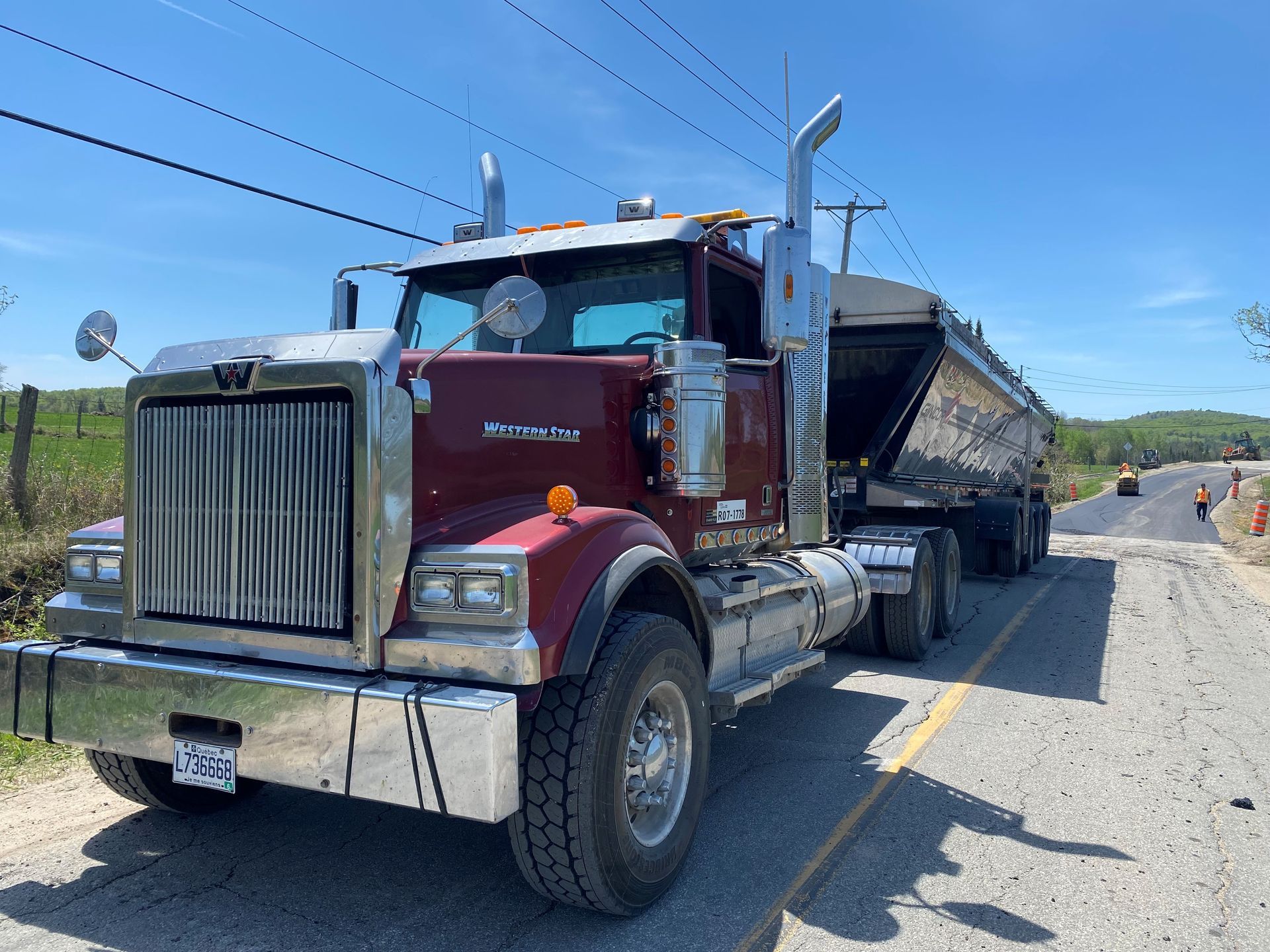 Un semi-camion rouge est garé sur le bord d'une route.
