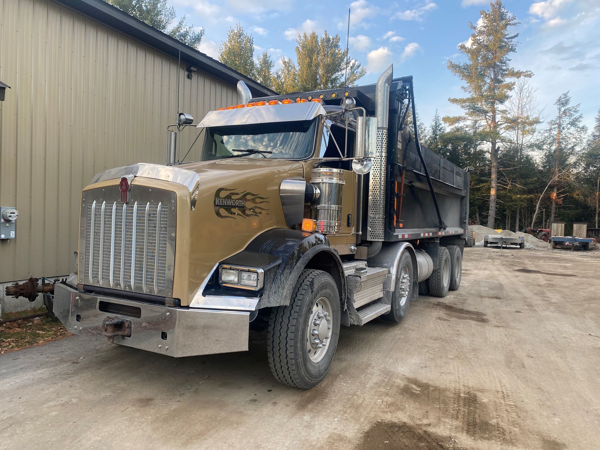 Un camion à benne basculante est garé devant un bâtiment.