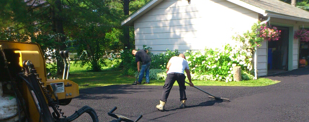 Un homme balaie une allée devant une maison.