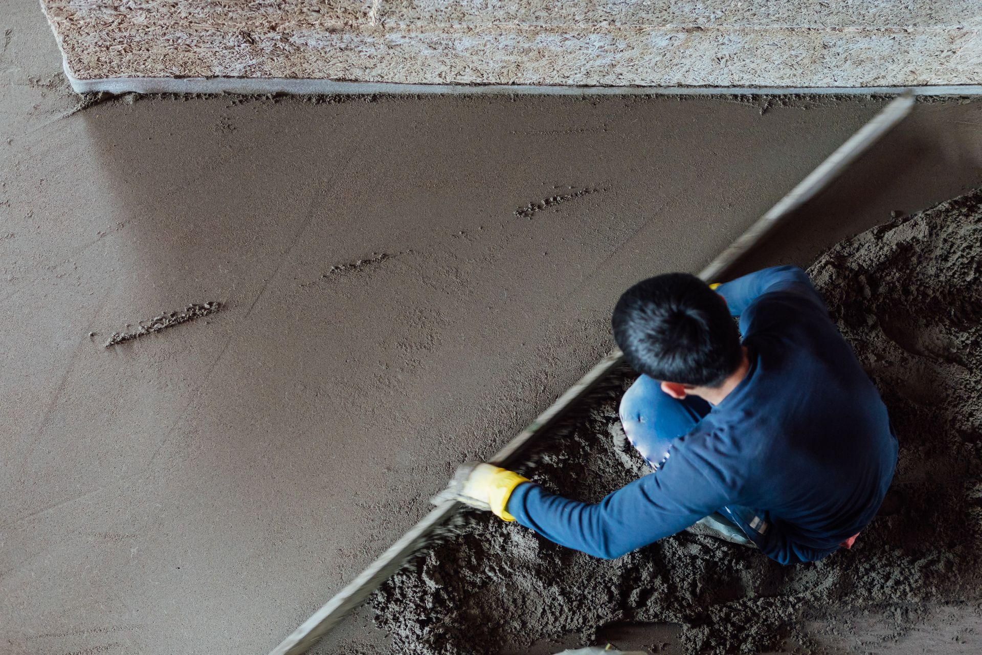 The top view of a mason smoothing a concrete floor. The top view of a mason smoothing a concrete floor.