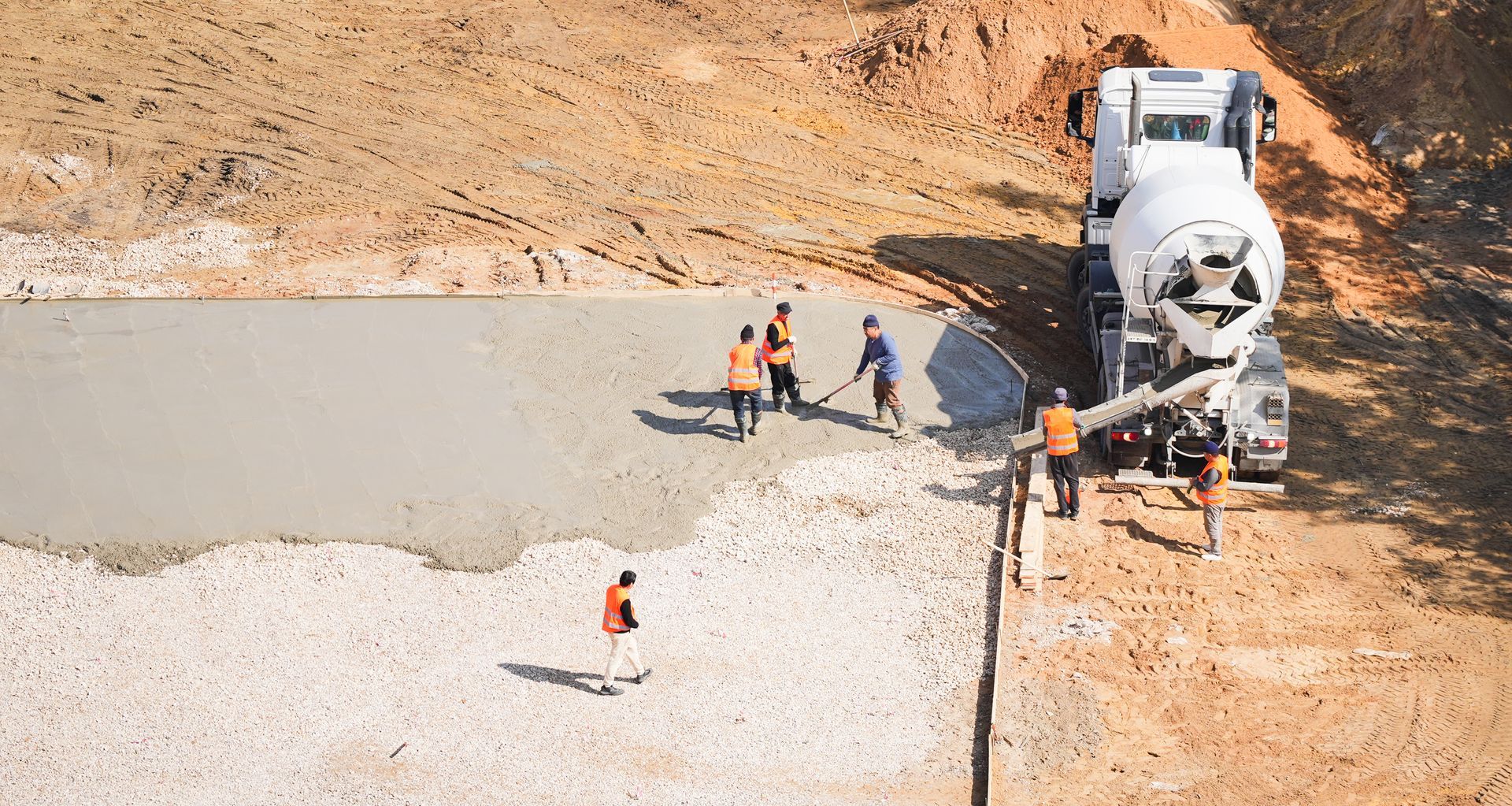 Aerial view of workers leveling fresh concrete from a mixer at a building site.