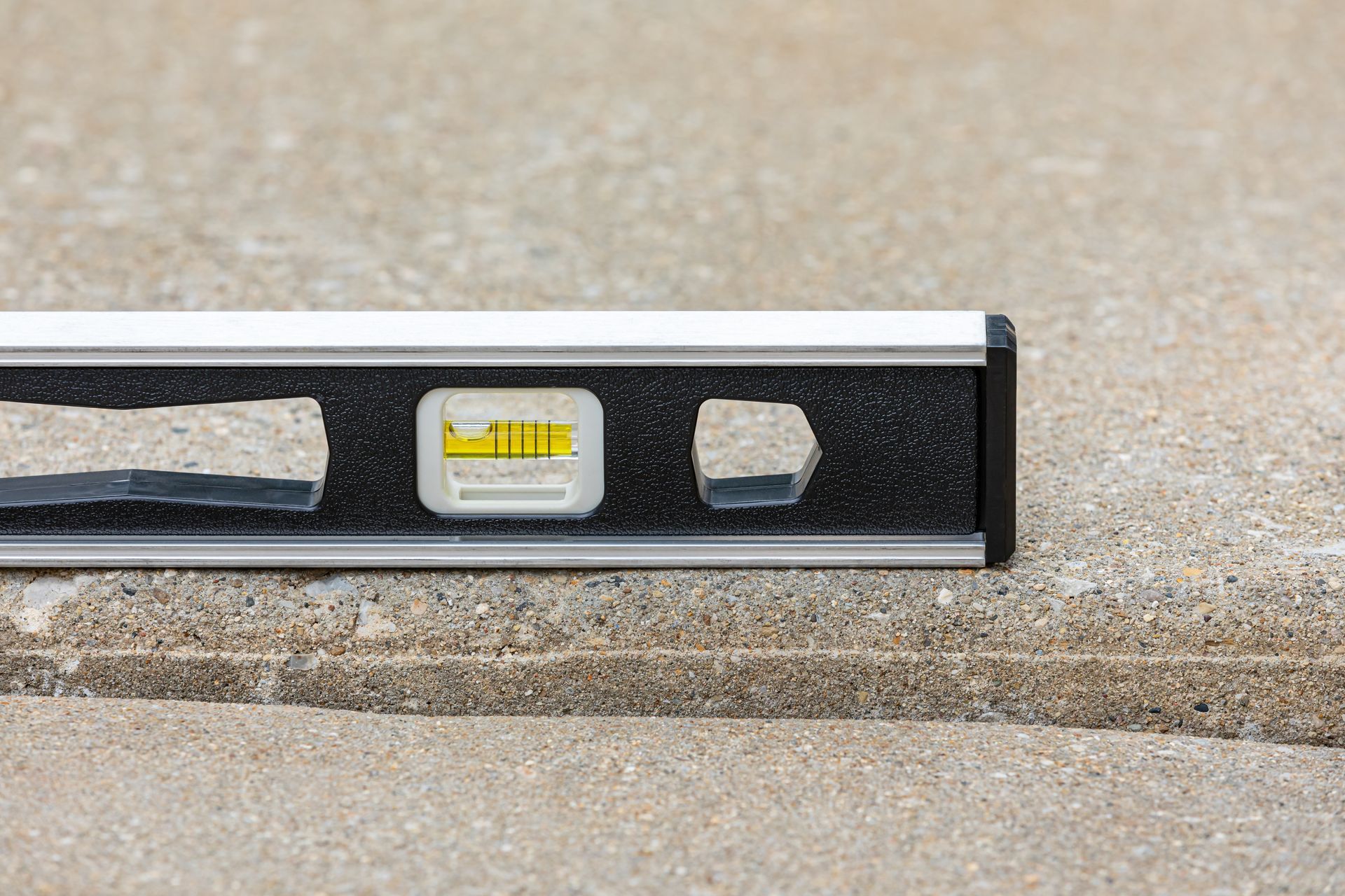 Bubble level resting on uneven concrete step to show misalignment before repair.